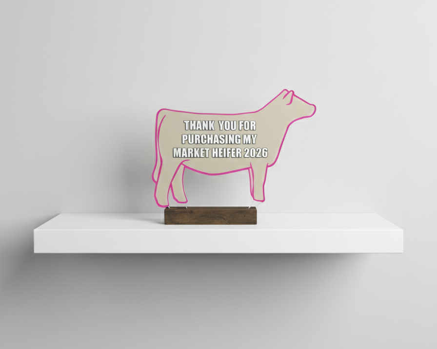 Decorative sign shaped like a cow on a white shelf with a gray background