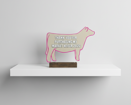 Decorative sign shaped like a cow on a white shelf with a gray background