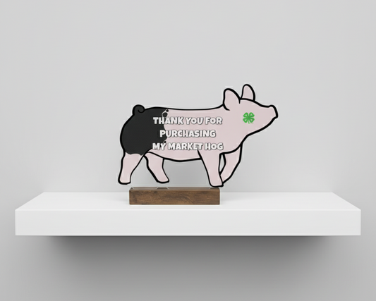 Decorative pig-shaped sign on a white shelf with a gray background